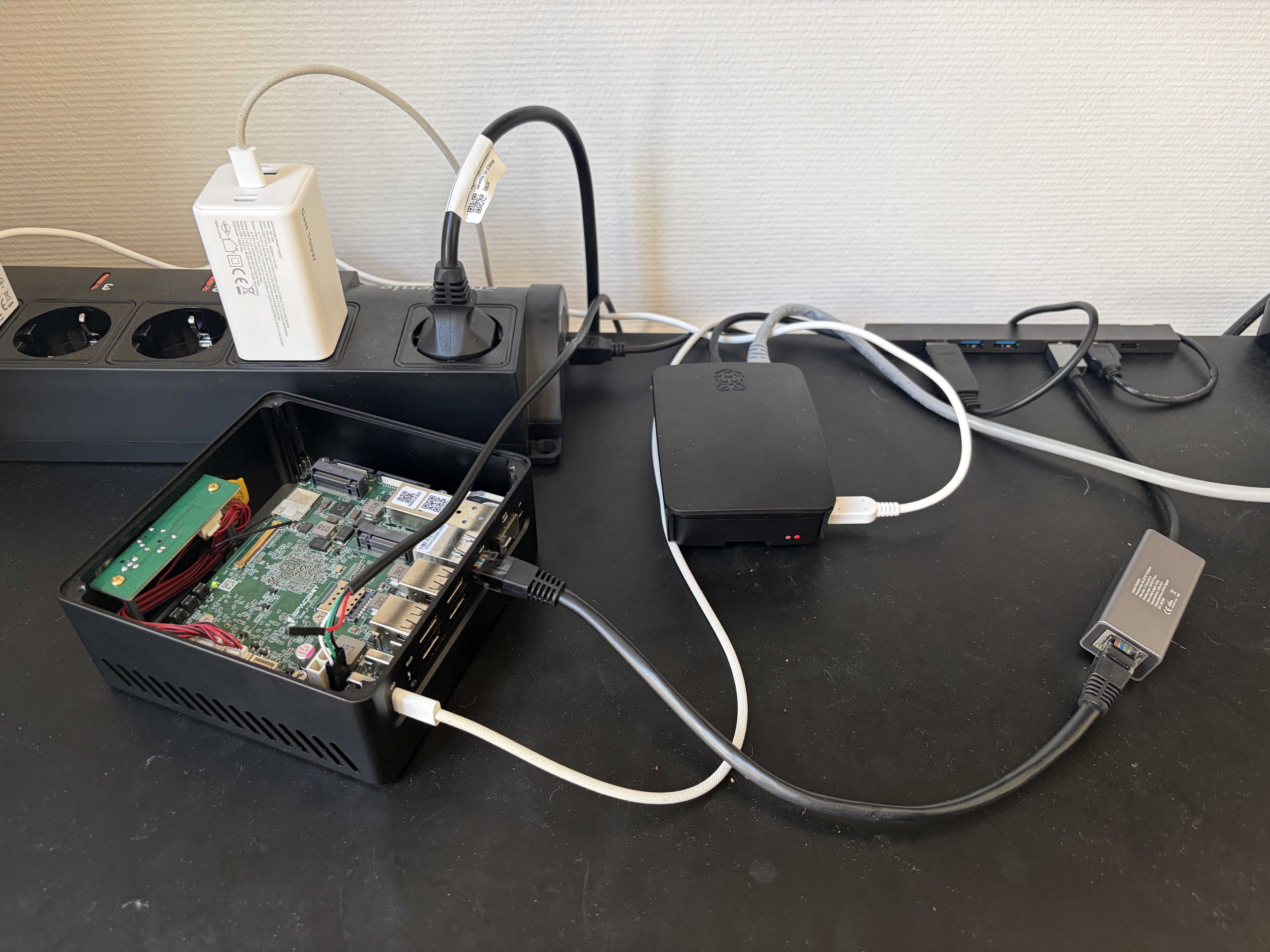 My desk with a Spacemit K3, a Raspberry Pi 3b+, and all the cables to connect Serial, Network, and Power